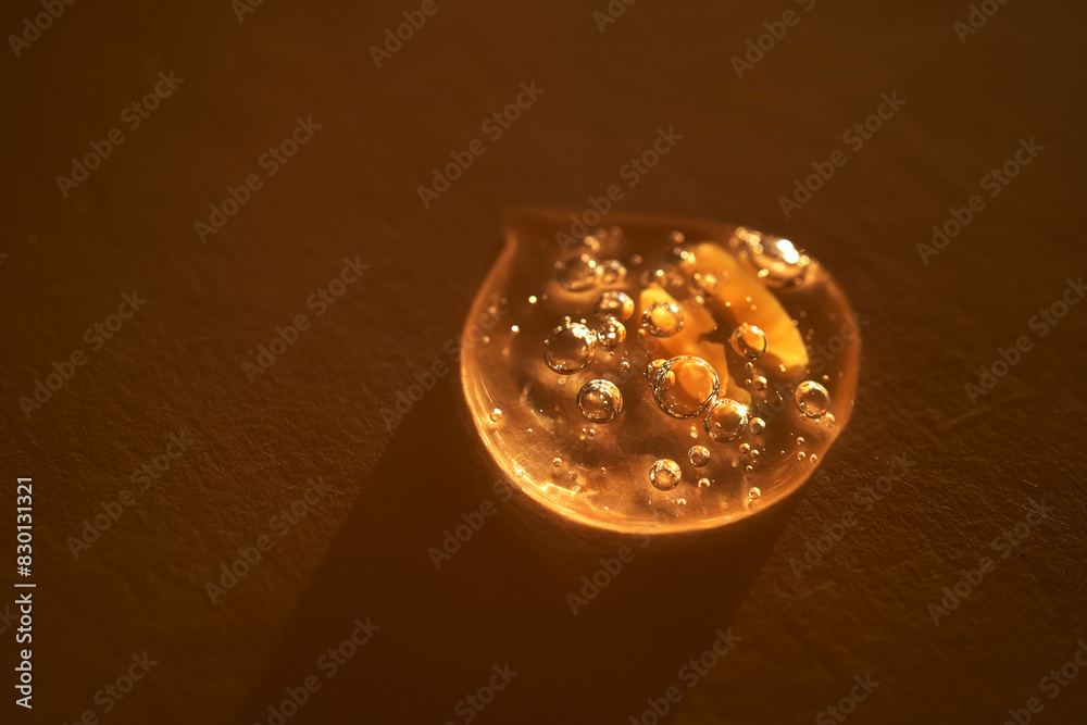 Drop of serum shimmering in the sun on a beige background. Drop of serum shimmering in the sun on a beige background.
