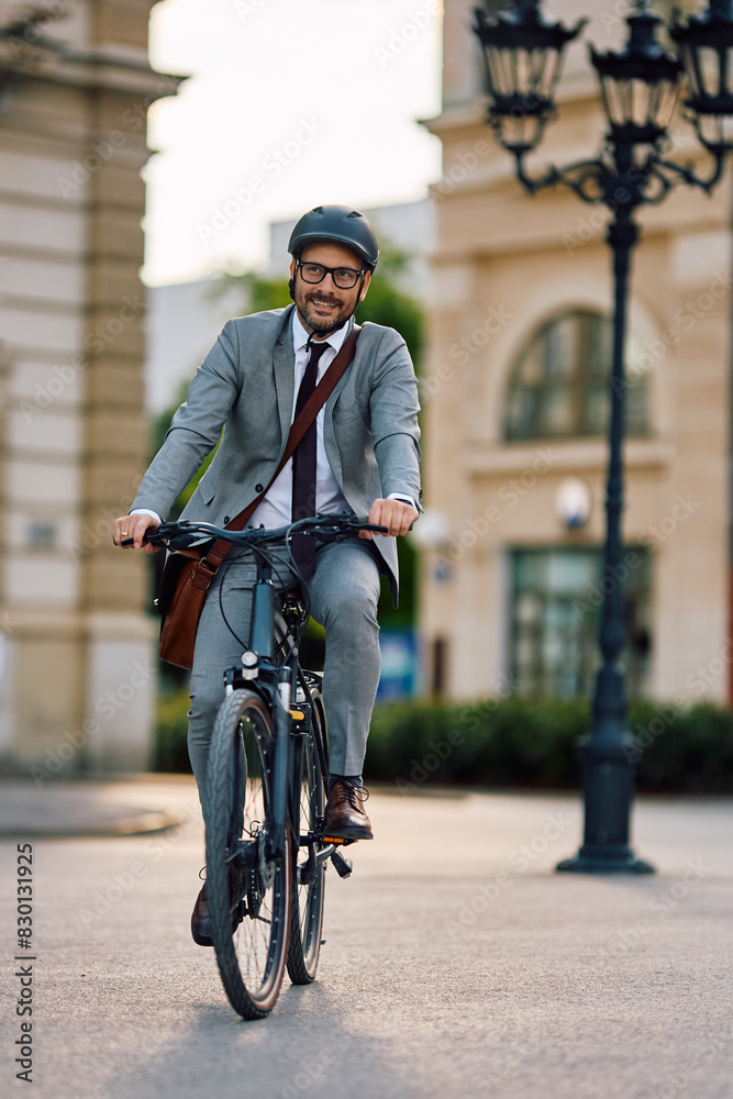 Smiling businessman riding on his bicycle through \ity.