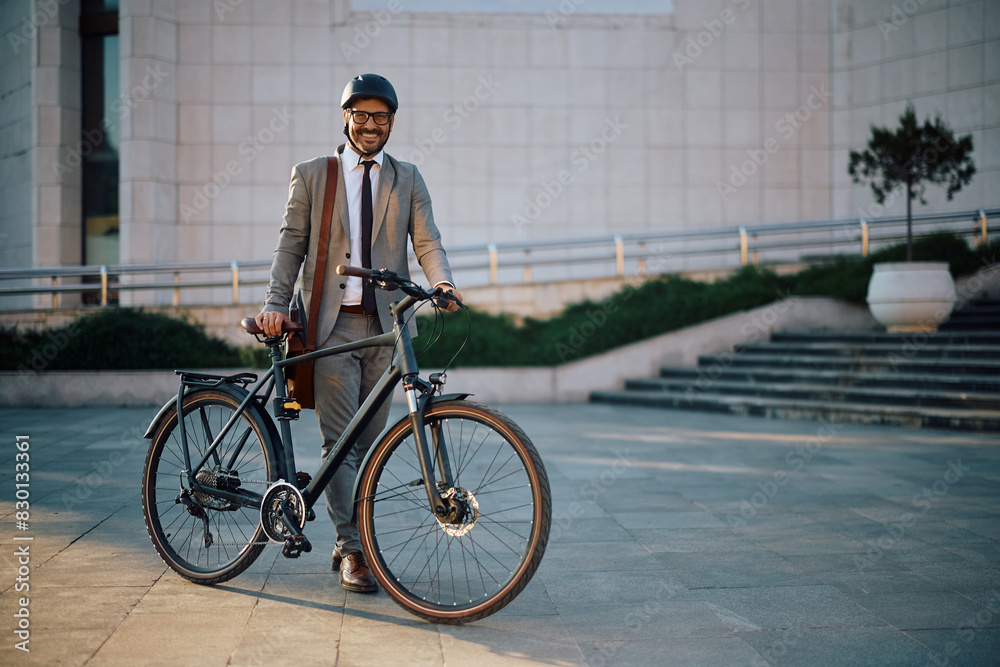 Happy businessman with his bike in city looking at camera.