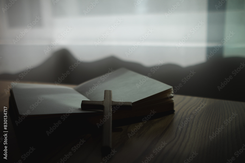 cross is placed on the Bible after prayer to God, which is religious ritual of Christianity and belief in the teachings of God. concept of praying to God with the teachings of the Bible and cross.