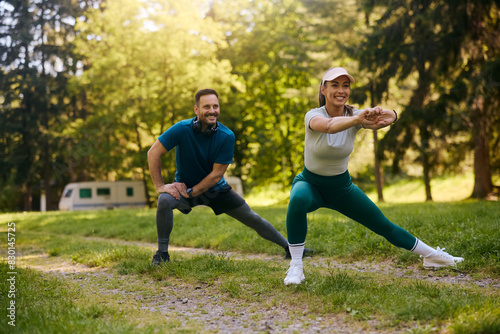 Happy couple doing stretching exercises while working out in nature.