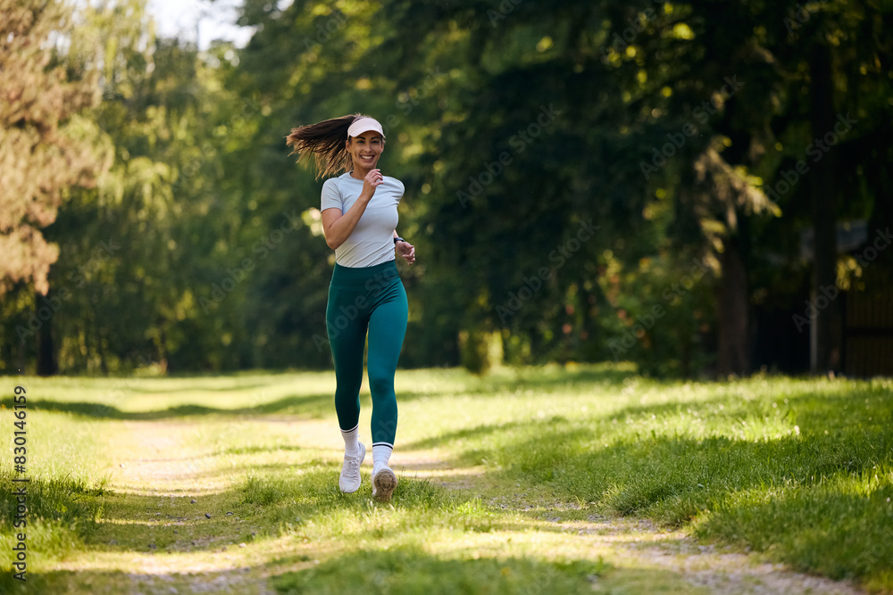 Full length of happy sportswoman jogging in  park.