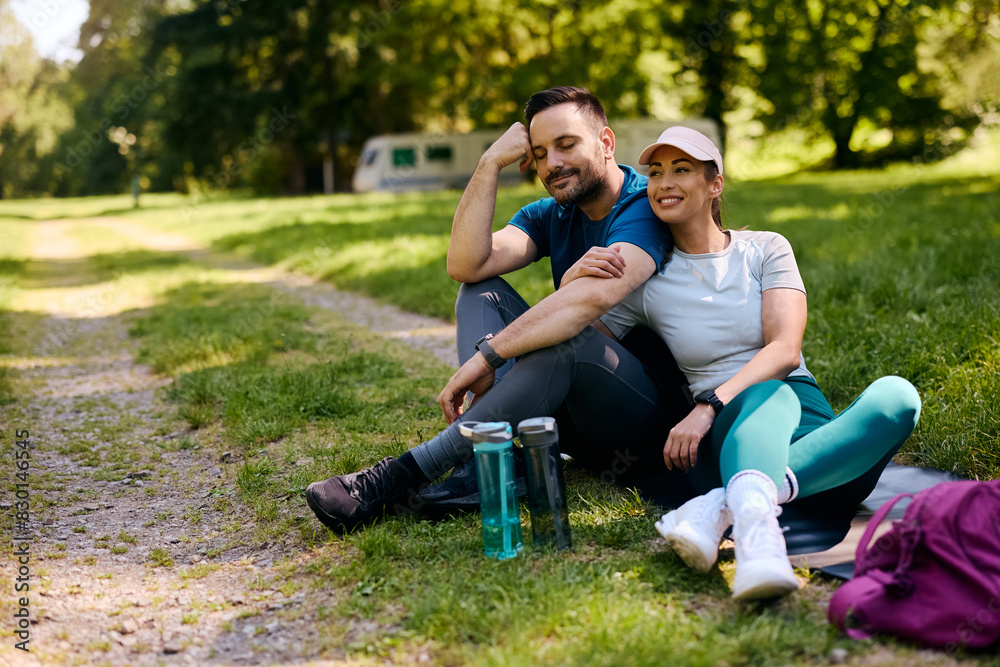 Fototapeta premium Athletic couple relaxing after exercising in park.