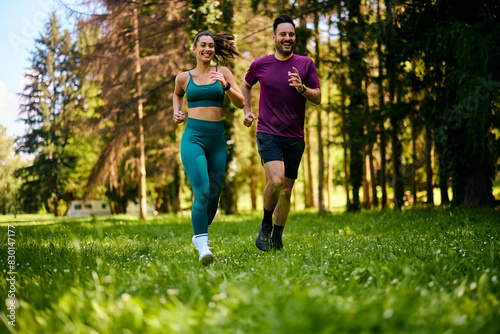 Happy sports couple enjoying in jogging through  park. © Drazen