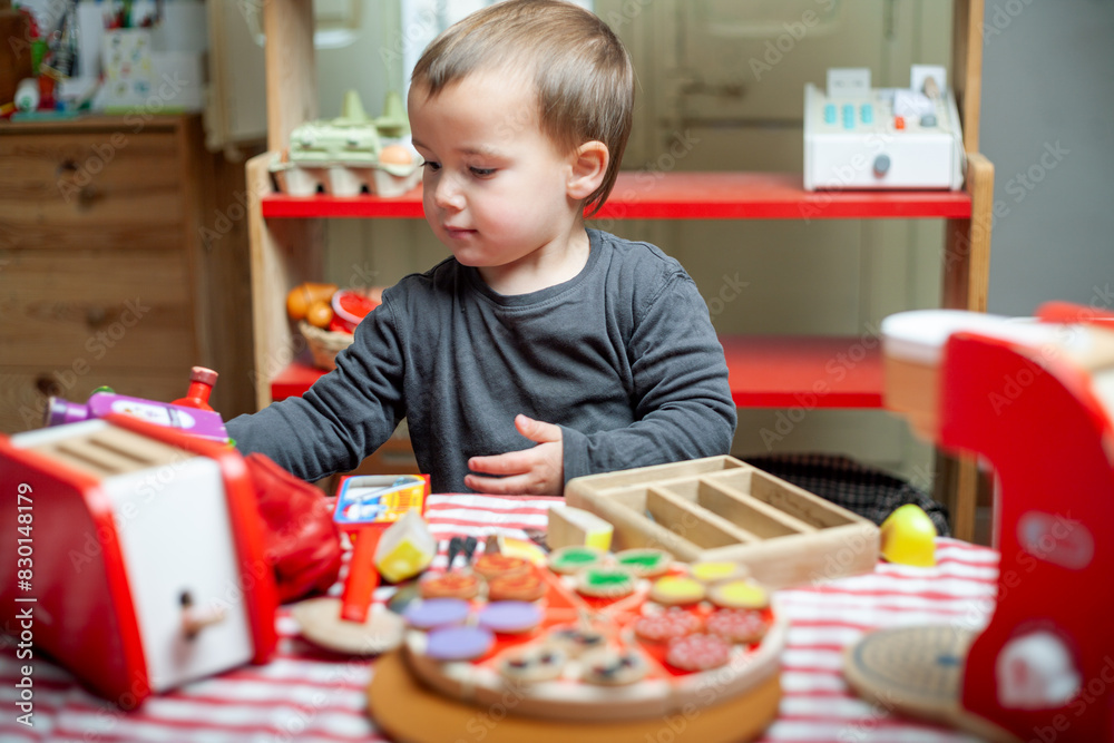 Toddler playing as a cook with wooden toys. Symbolic play, learning, growing. Toddler playing as a cook with wooden toys. Symbolic play, learning, growing.