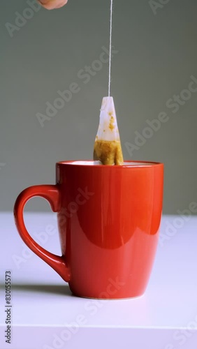 An orange mug with a teabag sits on a white surface, illuminated by daylight, creating a calm kitchen atmosphere.
