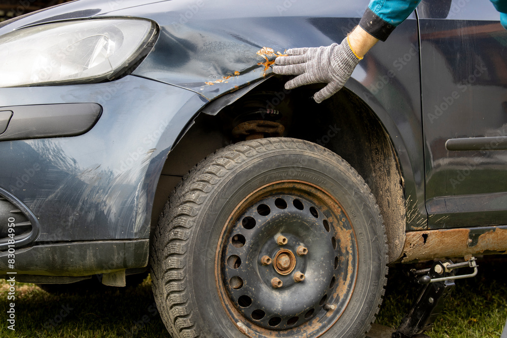 Fototapeta premium A person in blue gloves skillfully fixes the tire of a black car.