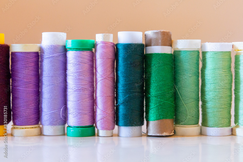 Variety of colorful thread spools on a table Variety of colorful thread spools on a table