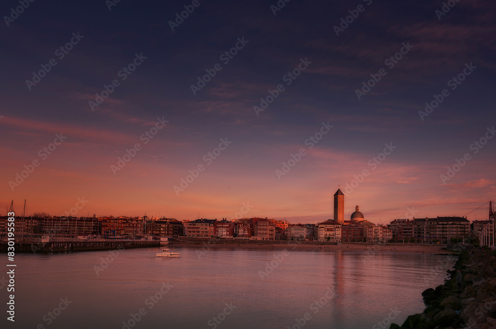Dusk skyline of Las Arenas, Getxo, with the Las Mercedes church standing out and the reflection of the lights in the sea