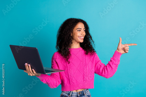 Photo portrait of pretty teen girl hold netbook point look empty space wear trendy pink outfit isolated on aquamarine color background © deagreez