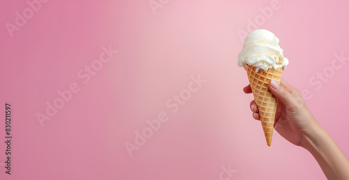 Illustration commerciale estivale, image gourmande, glace à la vanille dans la main d'une femme, fond rose uni photo