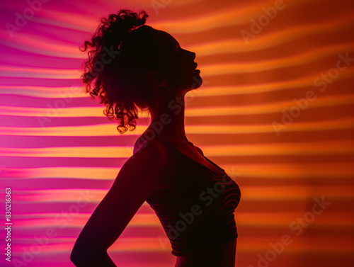 Silhouette of a beautiful woman dancing against a background of warm colors