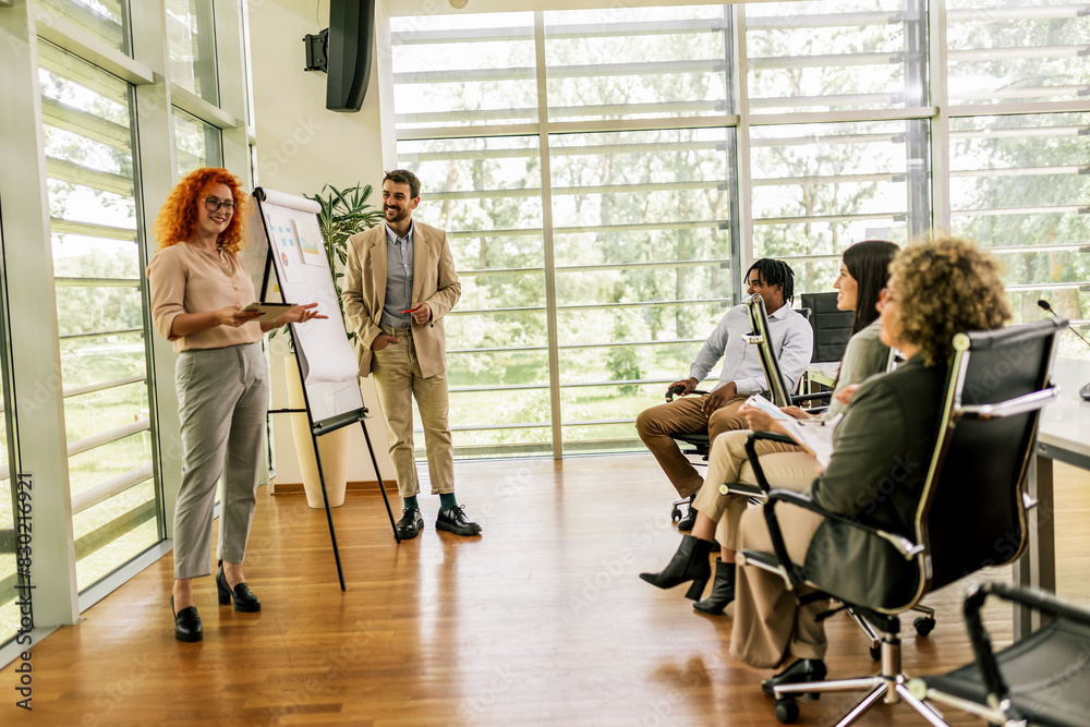 Ginger businesswoman and businessman showing their colleagues diagrams and graphics on a business meeting. Talk about growth of the firm and statistics.