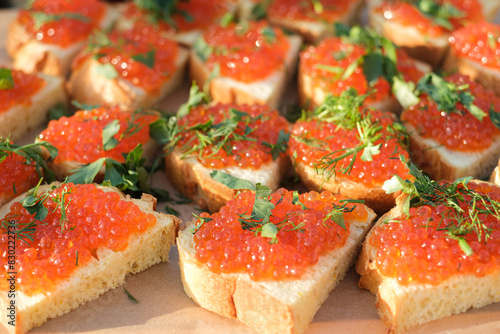 red salmon caviar on white bread sprinkled with green parsley and dill