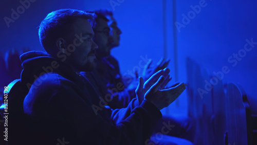 Men applaud performance in theater. Media. Men sit in one row and clap for performance. Theatrical performance with dark hall and applauding audience