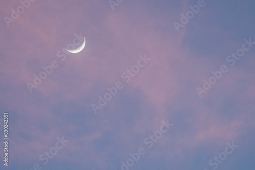 Crescent moon with cluds in dusk sky photo