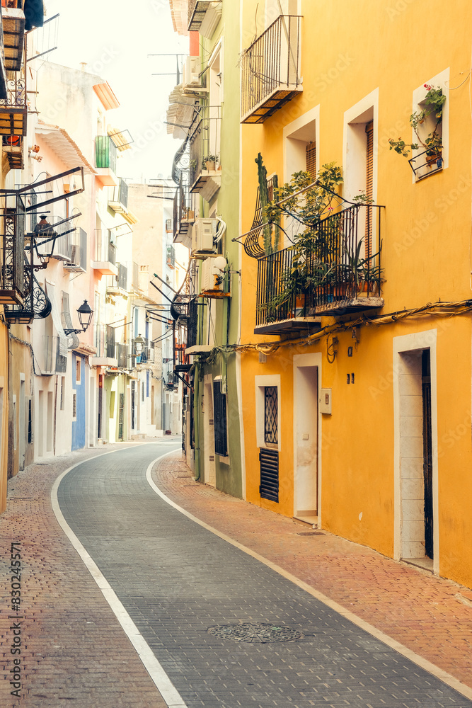 Naklejka premium View to beautiful narrow Villajoyosa street with multi-colored houses. La Vila Joiosa - coastal town, Valencian Community, Spain, by Mediterranean sea