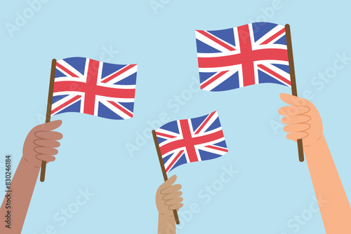 Diverse people hands raising flags of United Kingdom. Vector illustration of UK flags in flat style on blue background.