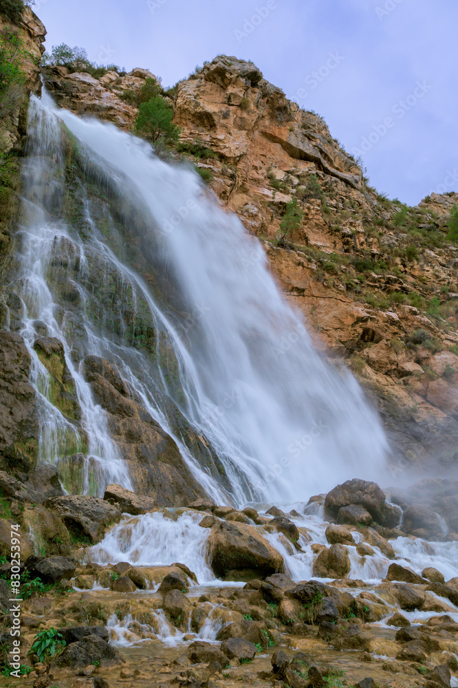 The image shows a powerful waterfall cascading down a rocky cliff. The image shows a powerful waterfall cascading down a rocky cliff.