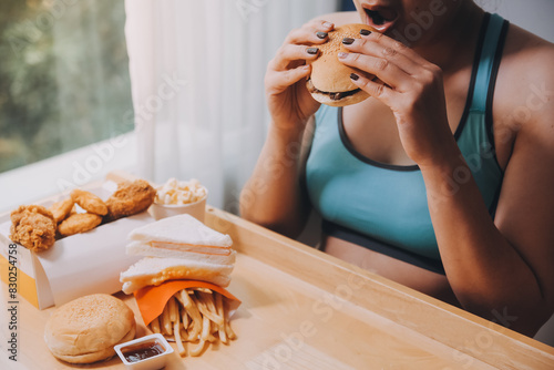 Binge eating disorder concept with woman eating fast food burger  fired chicken   donuts and desserts