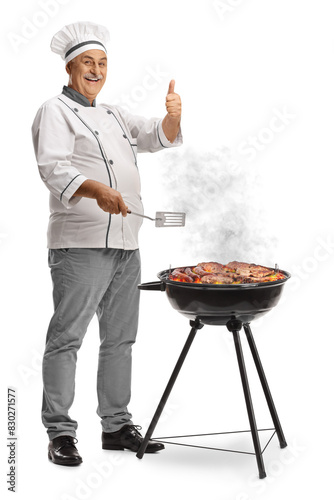 Mature male chef grilling meat on a bbq and gesturing thumbs up