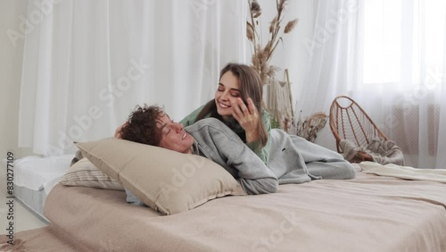 Young couple embraces and relaxes on a cozy bed in a bright room, enjoying peaceful moments together. slow motion, 4k