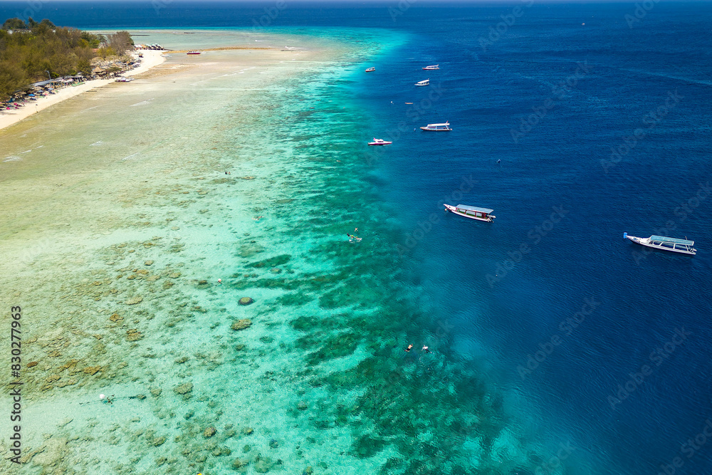 Obraz premium Snorkel and swim tour boats on the edge of a fringing tropical coral reef off a tropical island