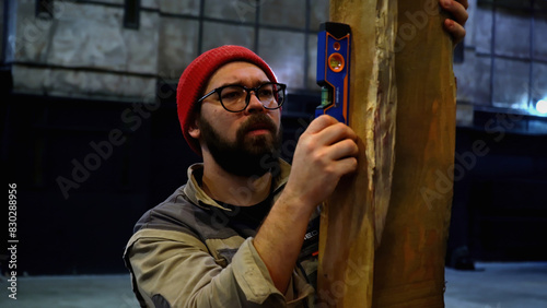 Cuadro en lienzo Carpenter using spirit level on wooden vertical beam