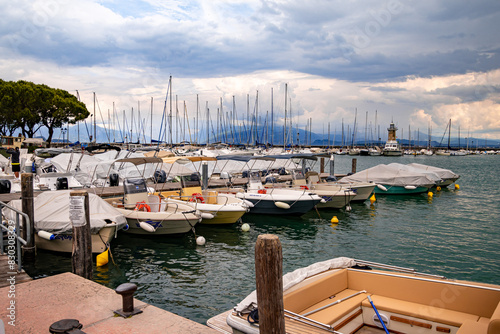 Desenzano, Lake Garda, Italy - 25 May 2024 Colorful motor- and sailingboats and lighthouse at harbor photo