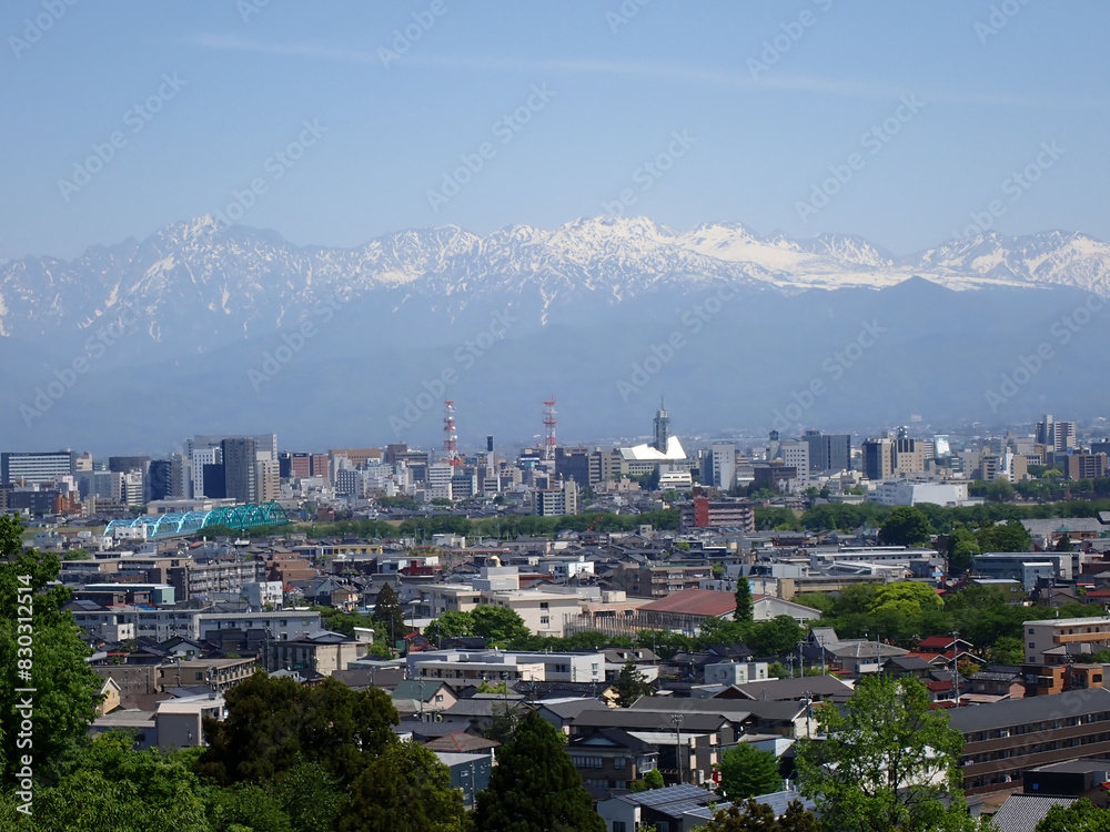 Fototapeta premium 5月新緑の呉羽山富山県道44号富山高岡線を跨ぐ遊歩道吊橋から北アルプス剱岳立山連峰富山市街地を望む