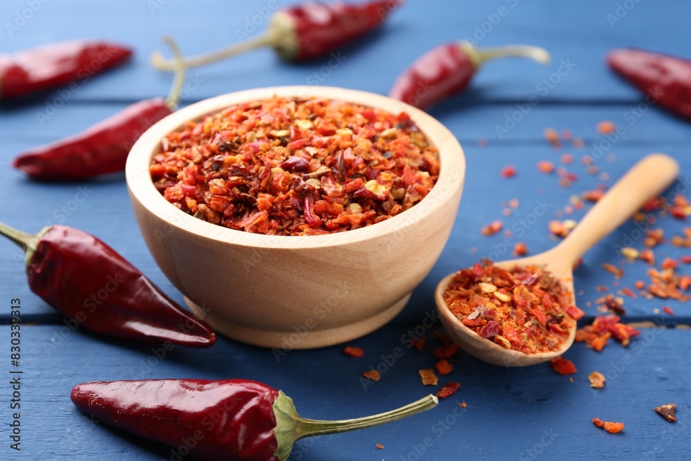Chili pepper flakes and pods on blue wooden table, closeup Chili pepper flakes and pods on blue wooden table, closeup
