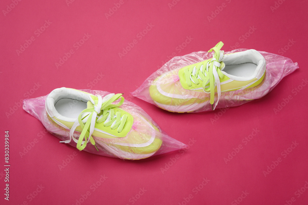 Sneakers in shoe covers on pink background, above view Sneakers in shoe covers on pink background, above view
