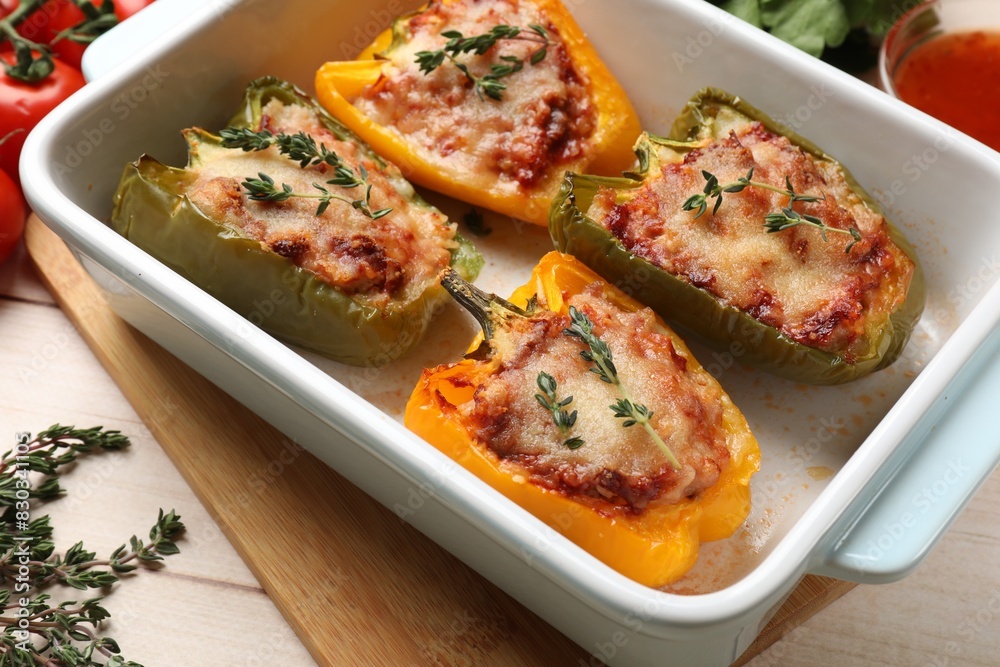 Tasty stuffed peppers in dish on wooden table, closeup Tasty stuffed peppers in dish on wooden table, closeup