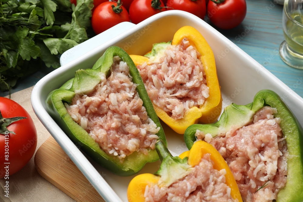 Raw stuffed peppers and ingredients on light blue wooden table, closeup Raw stuffed peppers and ingredients on light blue wooden table, closeup