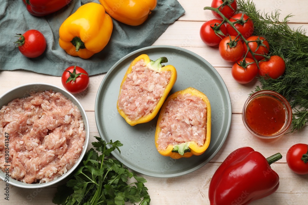Raw stuffed peppers with ground meat and ingredients on light wooden table, flat lay Raw stuffed peppers with ground meat and ingredients on light wooden table, flat lay