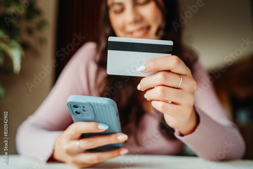One young caucasian woman is buying online on her laptop using credit card from her home	 photo