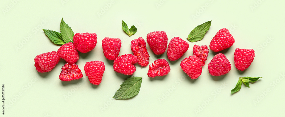 Many fresh raspberries and mint on light green background Many fresh raspberries and mint on light green background