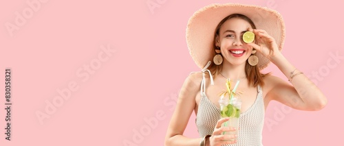 Beautiful young woman in beach hat and with tasty mojito on pink background with space for text