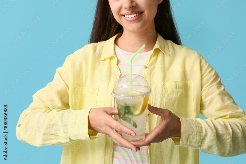 Beautiful young happy woman with cup of fresh lemonade on blue background, closeup Beautiful young happy woman with cup of fresh lemonade on blue background, closeup