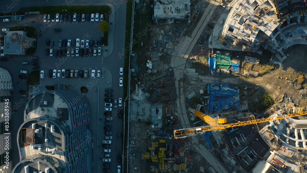 Top view of stadium construction. Stock footage. Construction site with cranes and machinery in city center. Construction of sports arena in city on sunny summer day