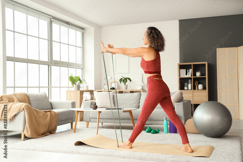 Sporty mature woman with stretching band doing yoga at home Sporty mature woman with stretching band doing yoga at home