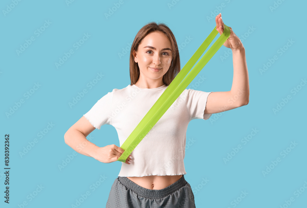 Sporty young woman with stretching band on blue background Sporty young woman with stretching band on blue background