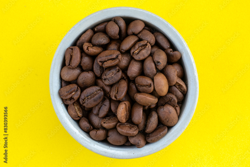 Ceramic pot with roasted coffee beans on a yellow background in Brazil Ceramic pot with roasted coffee beans on a yellow background in Brazil