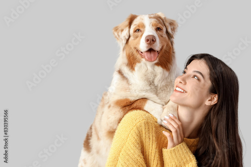 Young woman with Australian Shepherd dog on light background, closeup photo