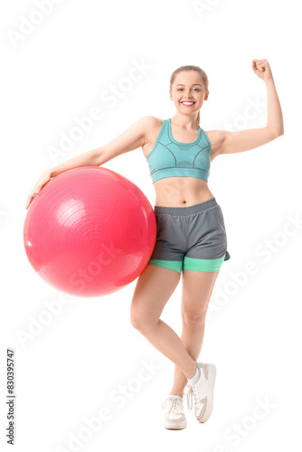 Sporty young woman with fitball showing muscles on white background