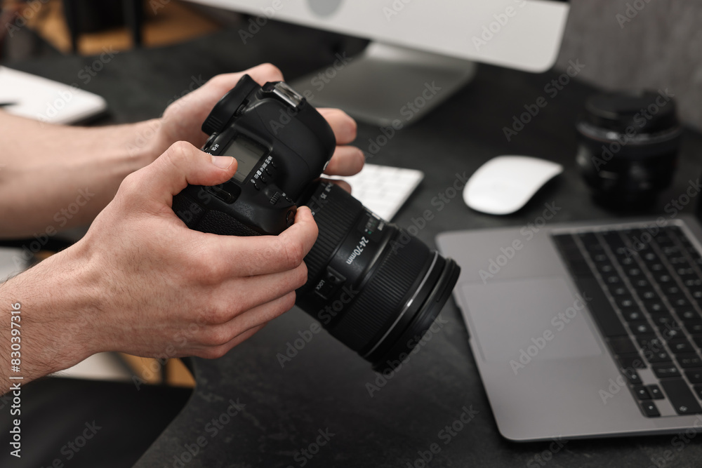 Photographer holding camera at dark table, closeup