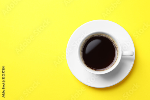 Cup of aromatic coffee on yellow background, top view. Space for text