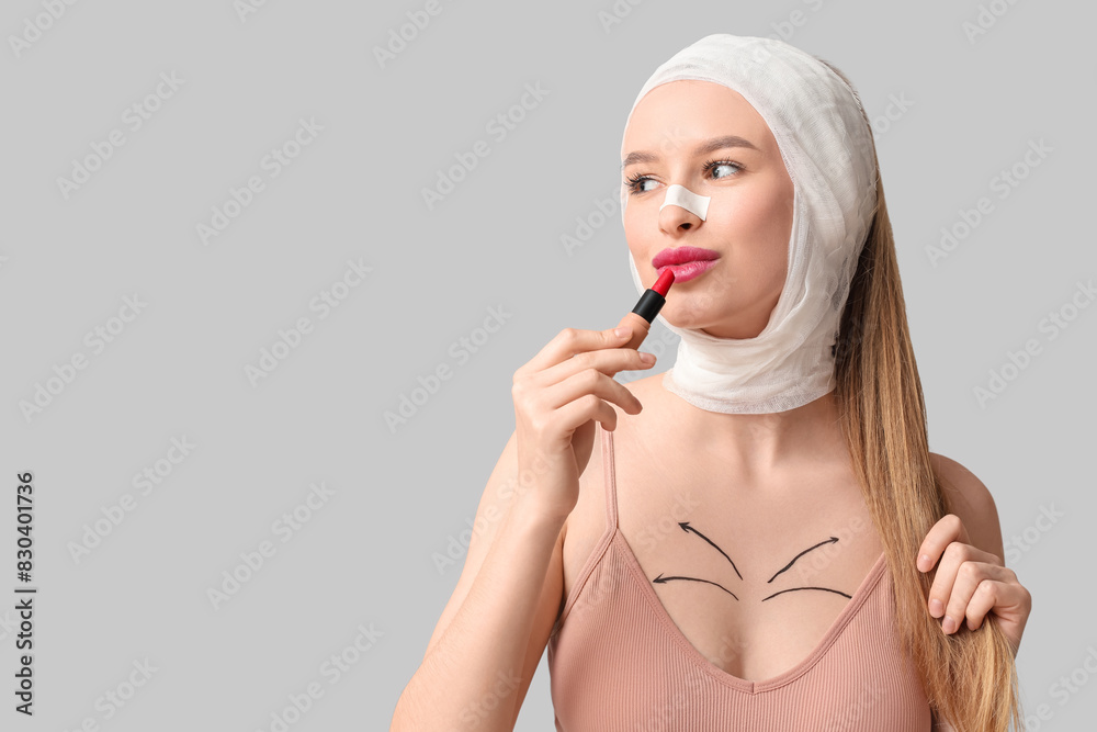 Young woman with bandaged head applying lipstick on light background, closeup. Plastic surgery concept Young woman with bandaged head applying lipstick on light background, closeup. Plastic surgery concept