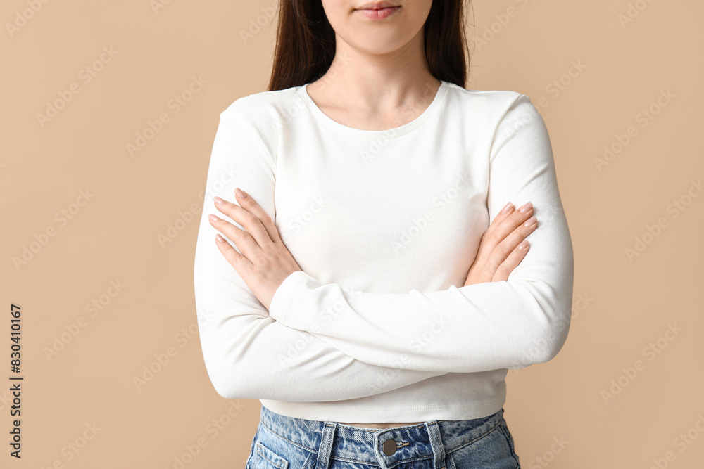 Fototapeta premium Pretty young woman in stylish white long-sleeve on beige background