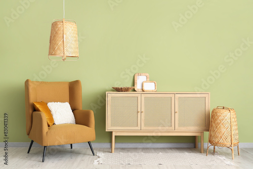 Brown armchair and wooden cabinet near green wall photo